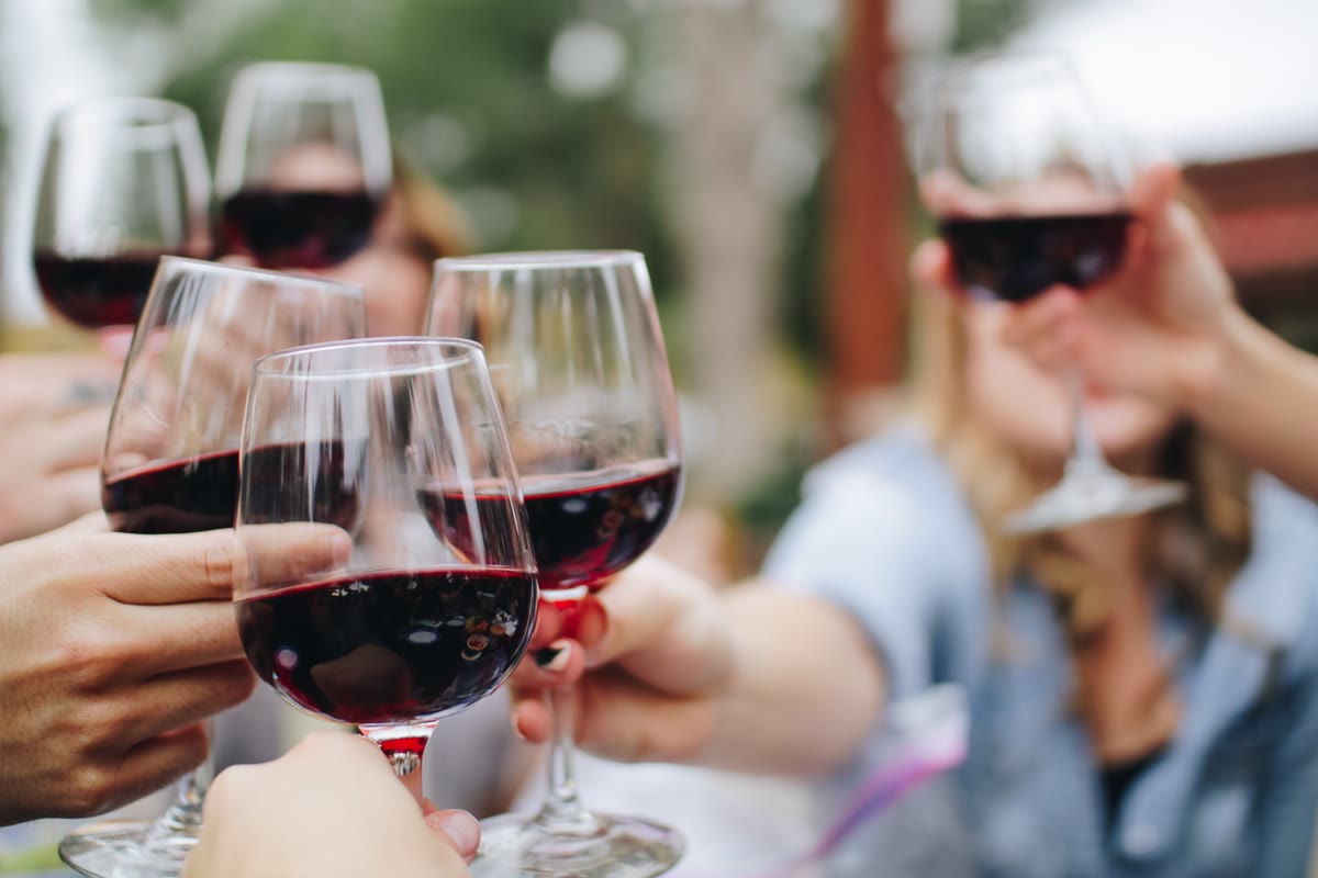 Gasten die met glazen rode wijn proosten op het terras