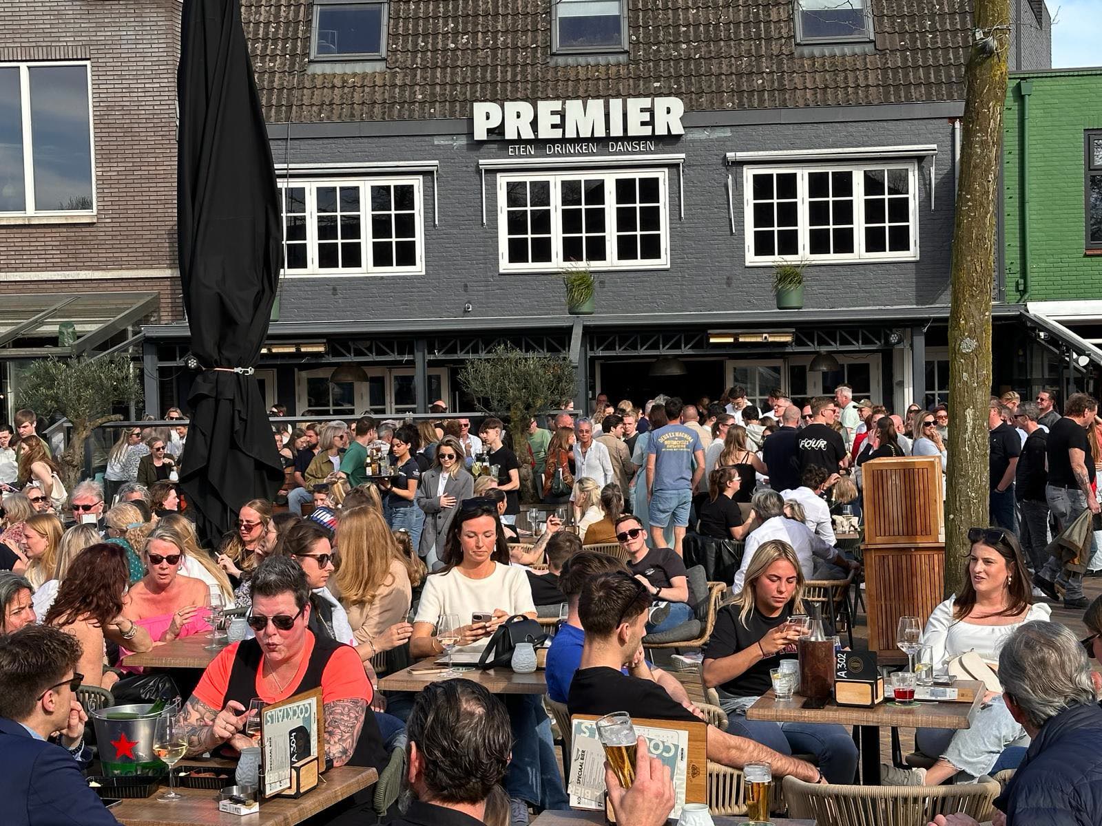 Het zwarte pand van Café Premier aan de Nieuwe Stationsstraat met een vol terras