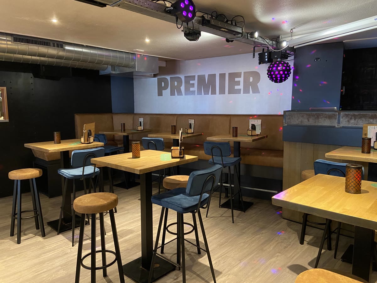 De bar binnen met houten krukken en de verlichte naam Premier